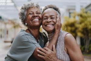 Two smiling women embracing, illustrating the importance of community and care in women's health screening and prevention